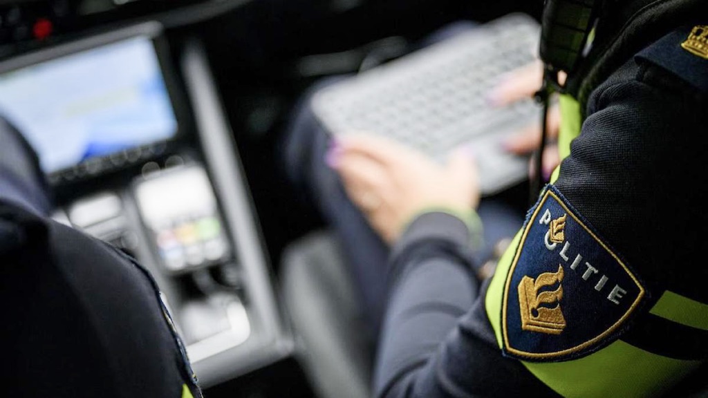Agent van de politie werkt digitaal samen achter een laptop